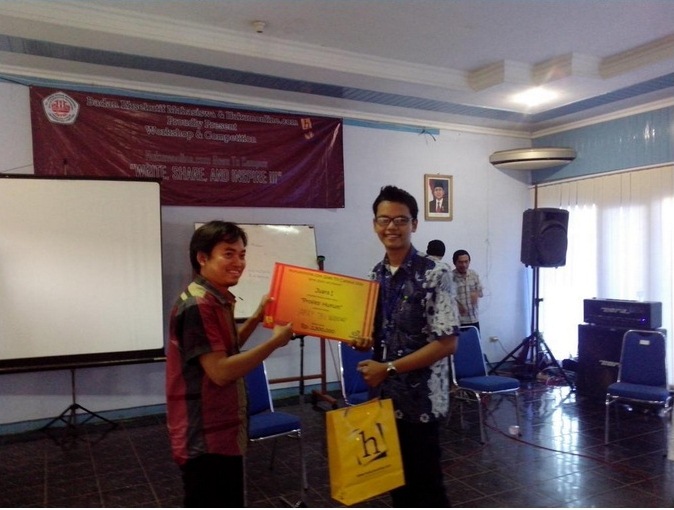 Pemred Hukumonline Abdul Razak Asri (kiri) menyerahkan hadiah kepada pemenang kompetisi penulisan Hukumpedia, Arief Triwibowo (kanan). Foto: Hukumpedia