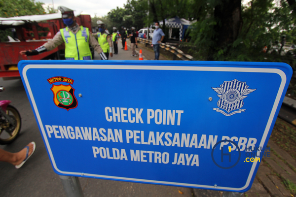 Anggota polisi saat melakukan check point pengawasan pelaksanaan PSBB di Jakarta.  Foto: RES
