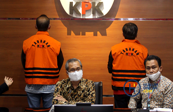 Dua tersangka Aries dan Ramlan mengenakan rompi oranye tahanan KPK berdiri membelakangi kamera yang diperlihatkan KPK saat konferensi pers. Foto: RES