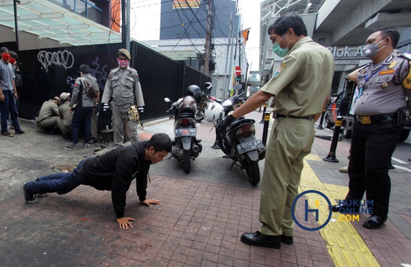 Seorang warga dihukum oleh petugas karena tidak menggunakan masker saat PSBB. Foto: RES