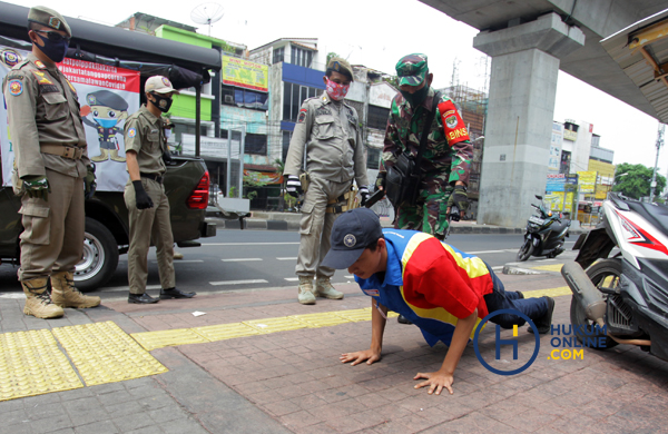 Petugas gabungan memberi hukuman push up kepada warga yang tidak memakai masker saat razia di Kawasan Jalan Fatmawati, Jakarta, Kamis (30/4) lalu. Foto: RES