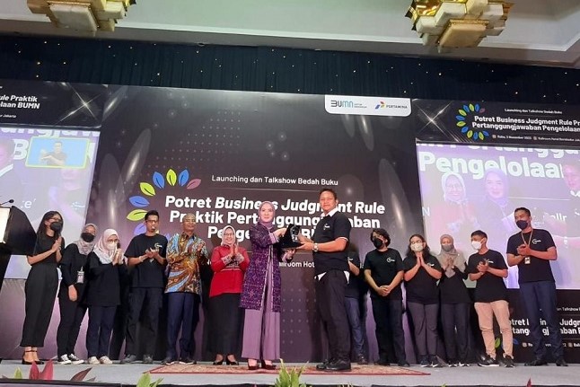 Ketua Tim Penulis Buku Potret Business Judgement Rule, Tatu Aditya menerima plakat penghargaan dari Direktur Utama PT Pertamina (Persero), Nicke Widyawati. Foto: istimewa.
