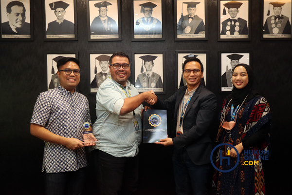 Chief of Engagement & Media Hukumonline Amrie Hakim saat menyerahkan laporan Top Indonesian Law Schools For Law Firm 2022 kepada Wakil Dekan Bidang SDM Adrianus Adityo Vito Ramon didampingi John Lumbantobing (kiri). Foto: RES  